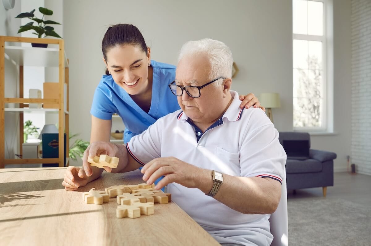 Memory care member helping an older adult with a puzzle