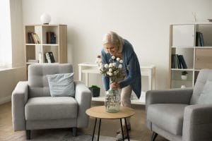 Older woman decorating her apartment with a flower vase