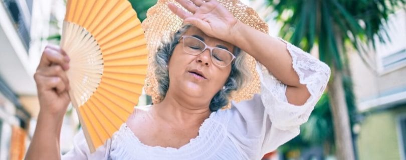Older woman cooling herself off with a hand fan