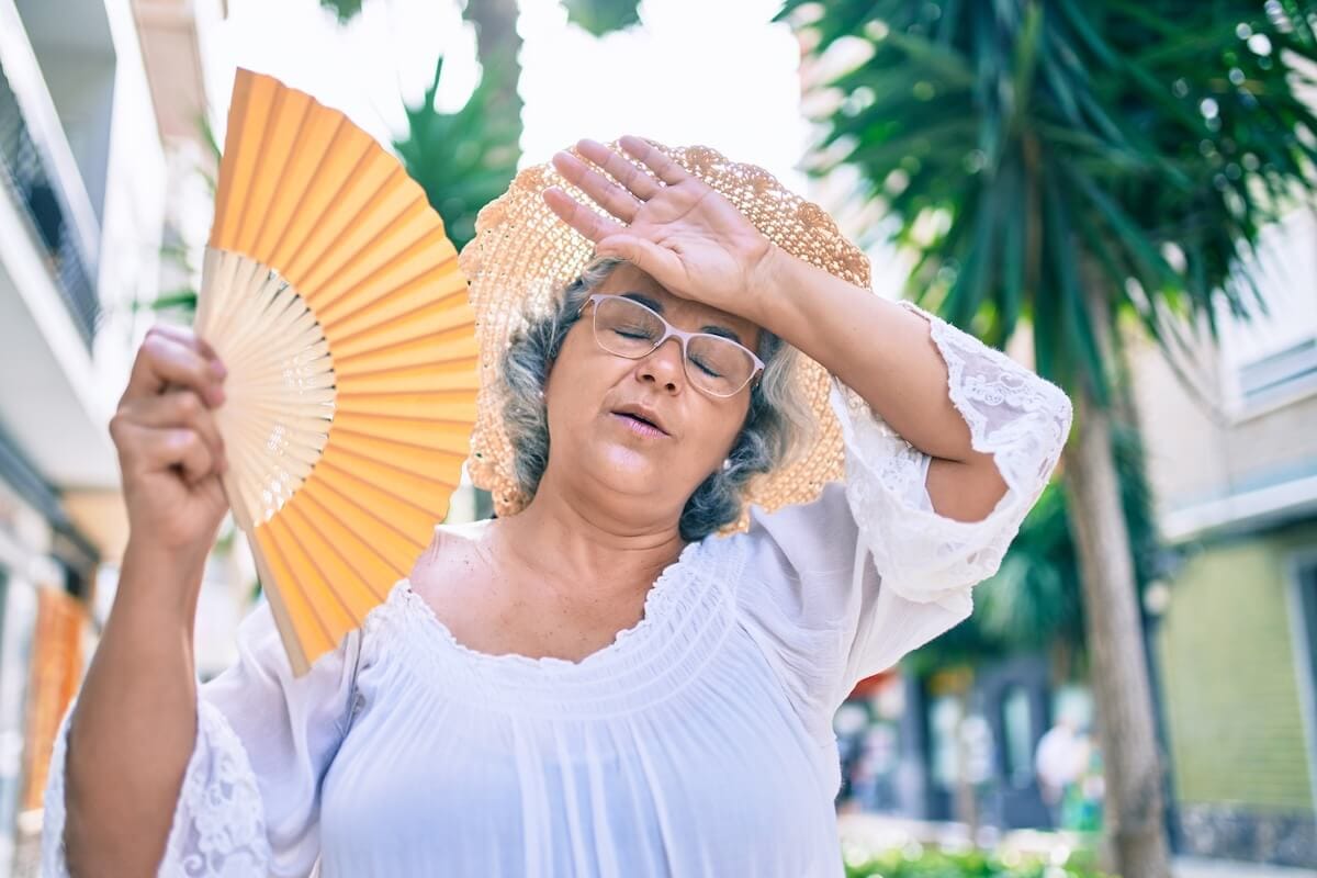 Older woman cooling herself off with a hand fan