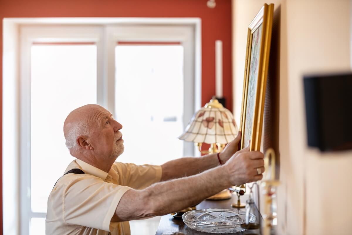 Older adult hanging an art print on a wall