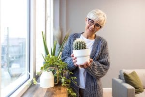 Happy older woman decorating her home with a plant