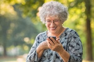 A smiling elderly woman holding a smartphone